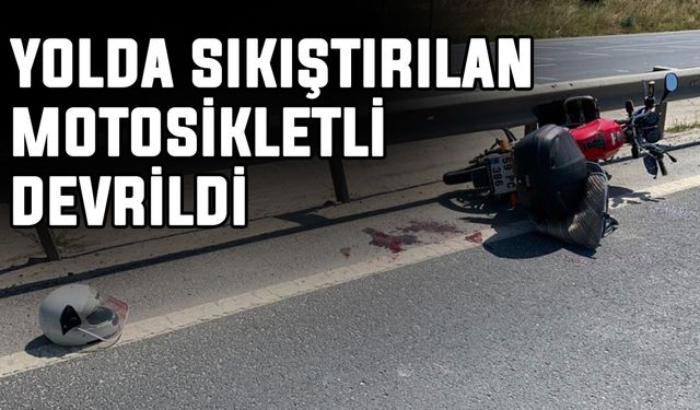 Yolda sıkıştırılan motosikletli devrildi